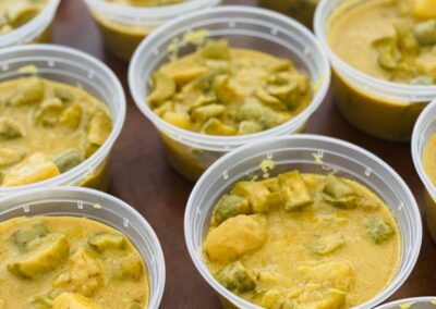 A group of plastic containers filled with yellow curry.