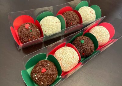 Truffles in holiday colored plastic boxes on a table.