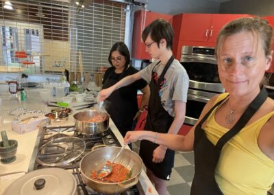 A group of people preparing food in a kitchen during a Classic North Indian Cooking Class with BeBe.