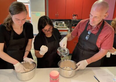 A group of people preparing food in a kitchen during the Classic North Indian Cooking Class with BeBe.