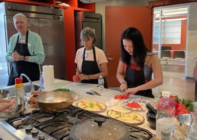 A group of people preparing food in a kitchen during the Lebanese Cooking Class with Jihan.