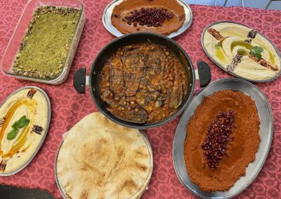 A table full of food on a pink tablecloth, featuring the Lebanese Cooking Class with Jihan.