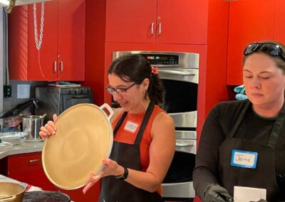 Two women preparing food in a kitchen during a Venezuelan Cuisine cooking class